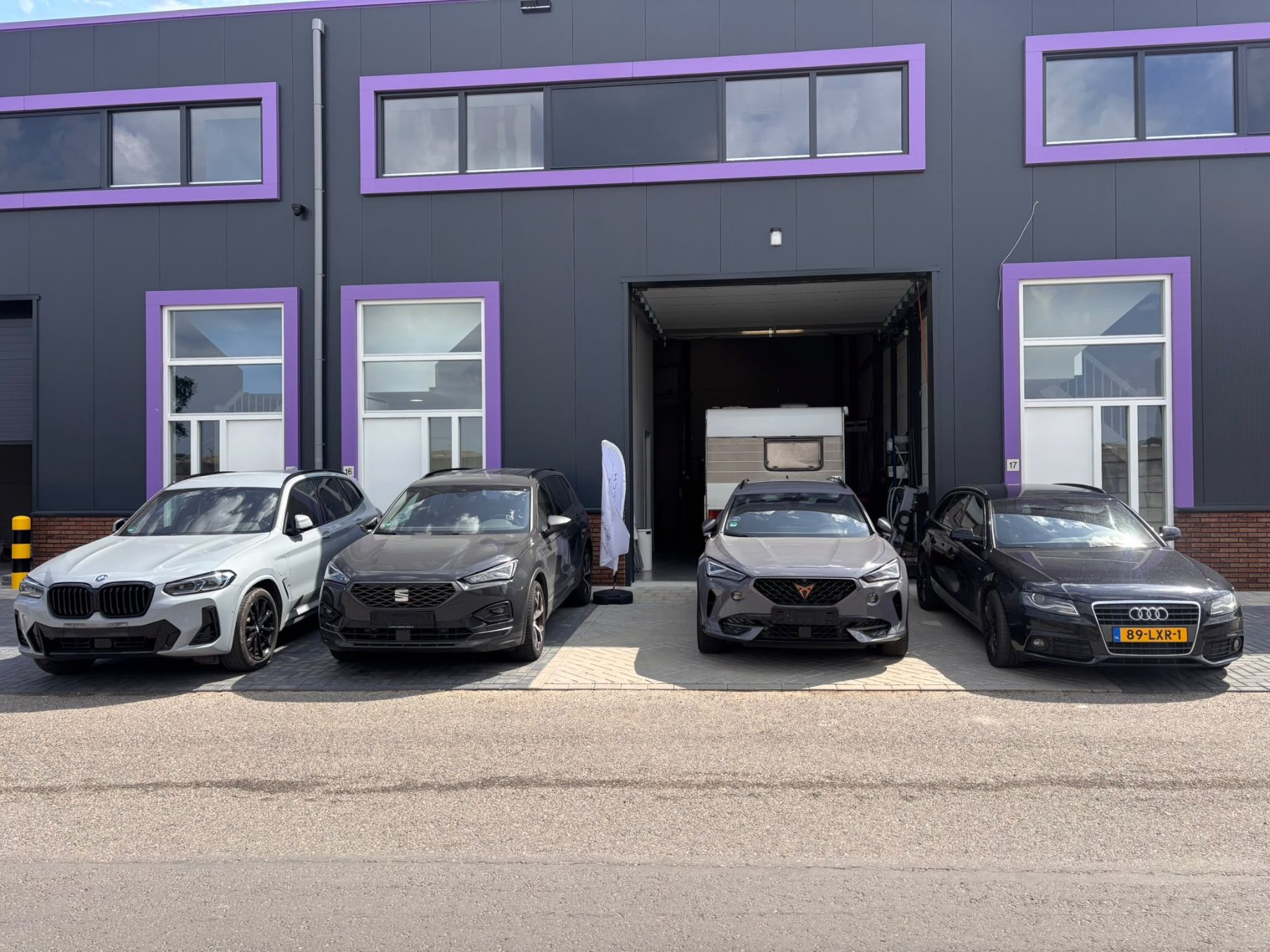 Werkplaats van DOUWTECH aan de Mobilisatieweg in Lopik met auto’s en een caravan